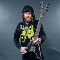 a man in a hoodie holding an electric guitar
